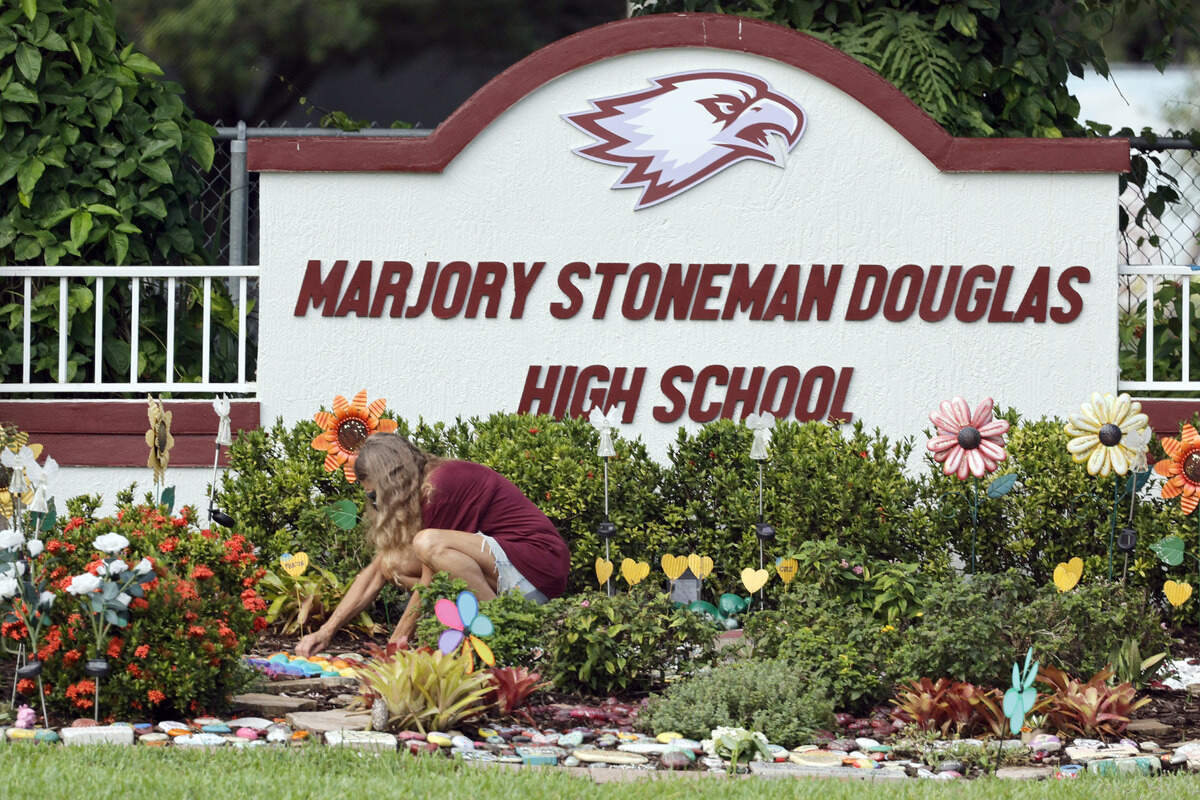 A woman clears debris on June 14, 2024, from a memorial garden at Marjory Stoneman Douglas High School in Parkland. An independent arbitrator has ruled the Broward Sheriff’s Office had every right to fire a deputy accused of running away from danger during the mass shooting at the school in 2018.